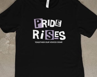 May include: Black t-shirt with a white graphic that says "PRIDE RISES" in a blocky font with purple accents. The text "TOGETHER OUR VOICES SOAR" is printed below the graphic.