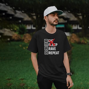 Puede incluir: Camiseta negra con un gráfico de lista de verificación blanca que dice "Comer, Dormir, Fiestar, Repetir". La palabra "Dormir" está tachada con una X roja.