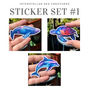 May include: A set of three galaxy-themed stickers featuring a whale, a sea turtle, and a dolphin. The stickers are printed on white vinyl and have a glossy finish.