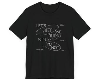 May include: Black t-shirt with white text that reads "LET'S GET ONE THING STRAIGHT I'M NOT." The text is arranged in a circular design with arrows. The shirt also includes the text "GAY SHOP" and "CA/USA".