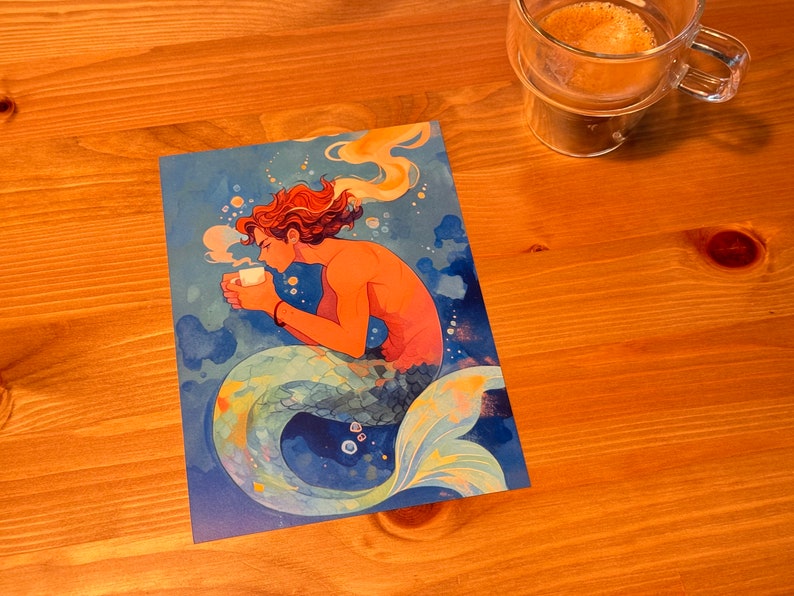 Może przedstawiać: Aquarelowe ilustracje syreny z pomarańczowymi włosami trzymającej białą filiżankę kawy. Syrena siedzi na niebiesko-zielonym ogonie z ż&oacute;łtymi i pomarańczowymi akcentami. Tło to niebiesko-zielony akwarelowy wash z białymi bąbelkami.