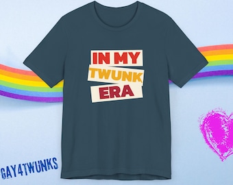 May include: A dark blue t-shirt with the text "IN MY TWUNK ERA" in a colorful, layered font. The text is in a white box with a red, yellow, and orange color scheme. The hashtag #GAY4TWUNKS is printed at the bottom of the shirt.