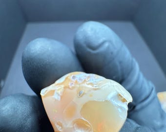 May include: A heart-shaped, orange and white opal with a rough, natural texture.