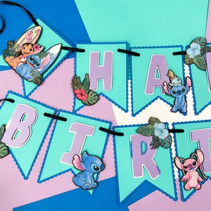 Puede incluir: Una colorida pancarta con las palabras "HAPPY BIRTH" en letras lavanda sobre banderines turquesa. La pancarta presenta im&aacute;genes de Stitch y otros personajes, junto con flores y hojas tropicales. Una cinta negra une los banderines.