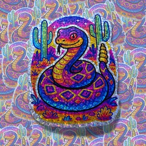 May include: A colorful sticker featuring a stylized snake with a desert theme. The snake is depicted in vibrant shades of purple, blue, yellow, and orange, with a desert landscape background and two cacti. The sticker has a glittery, iridescent finish.