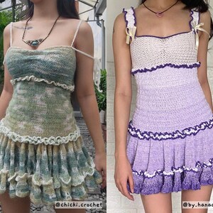 May include: Two handmade crochet dresses. One is green and white, the other is purple and white. Both dresses have a ruffled skirt and spaghetti straps. The green dress has a square neckline, and the purple dress has a sweetheart neckline.