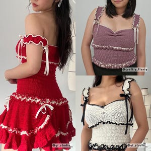 May include: A collection of handmade crochet tops and a dress. The red dress has a ruffled skirt and off-the-shoulder neckline. The tops are in mauve and white, with ruffled edges and bow details. The tops and dress are handmade.