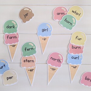 May include: A set of ice cream cone-shaped cards with different words and letter combinations. The words include "dark", "farm", "jar", "girl", "arm", "whirl", "born", "fur", "burn", "curl", "fern", "north", "stern", "hurt", "per", and "bird".