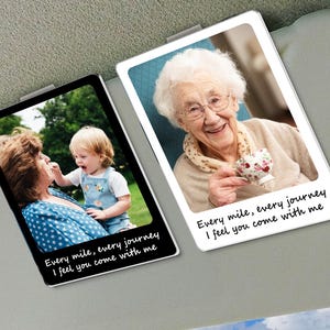 May include: Two rectangular car visor clips with photos. One shows a woman and a child, the other an elderly woman holding a teacup. Both have the text "Every mile, every journey I feel you come with me."