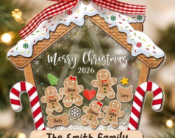 May include: A house-shaped Christmas ornament featuring a red and white gingham bow, a snowy roof with sprinkles, and two candy cane sides. The center displays gingerbread figures labeled with names, a red heart, and the text Merry Christmas 2026.