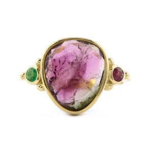 以下が含まれることがあります： ピンク、グリーン、ゴールドの大きな宝石がついたゴールドのリング。リングには、グリーンとレッドの小さな宝石が2つ付いています。