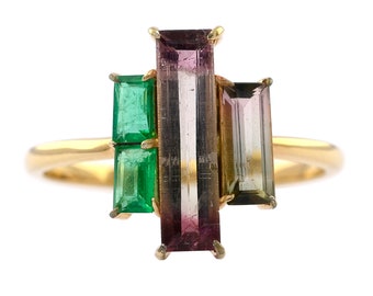 Può includere: Un anello d'oro con tre pietre preziose rettangolari. La pietra centrale è una tormalina multicolore, e le due pietre laterali sono smeraldi verdi.