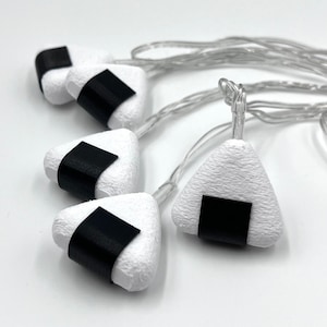 May include: A string of white triangle-shaped lights with black accents, resembling onigiri, a Japanese rice ball.