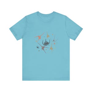 May include: A light blue t-shirt with a graphic design of abstract shapes in shades of pink, orange, and gray on a blue background.