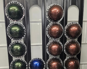 May include: A black metal stand with 10 round compartments for holding coffee pods. The compartments are filled with green and brown coffee pods.
