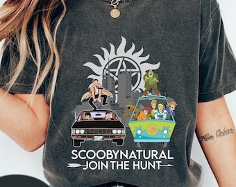 May include: A gray t-shirt with a graphic of the Scooby Doo van and the Supernatural car with the characters from both shows. The text "ScoobyNatural Join the Hunt" is printed on the shirt.
