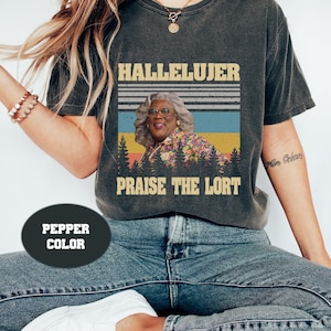 Könnte beinhalten: Ein dunkelgraues T-Shirt mit einer Grafik im Vintage-Stil, die eine Frau mit Brille und den Text "Hallelujer Praise the Lort" zeigt.
