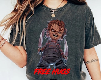 May include: A dark gray t-shirt with a graphic of a cartoon character holding two knives. The character has red hair and a mischievous expression. The text "FREE HUGS" is printed in red below the character.