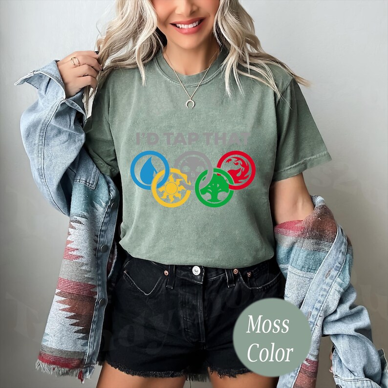 Pode incluir: Uma camiseta verde musgo com o texto "I'd Tap That" e um gr&aacute;fico de cinco an&eacute;is entrela&ccedil;ados com s&iacute;mbolos que representam os cinco elementos da magia: &aacute;gua, fogo, terra, ar e esp&iacute;rito.