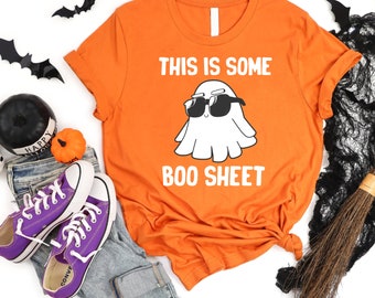 May include: Orange t-shirt with a white ghost wearing sunglasses and the text "This is some boo sheet".