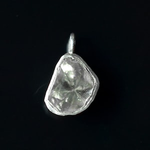 May include: A silver pendant featuring a clear, faceted gemstone with a rough, irregular shape.
