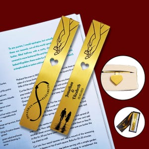 May include: Gold-colored metal bookmarks with a heart-shaped cutout and engraved designs. One bookmark features the names "Jonathan & Elizabeth" and the date "01.03.2013". The other has an infinity symbol with the names. A small heart-shaped bookmark is also visible.