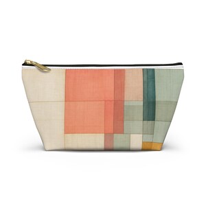 May include: A trapezoidal zippered pouch featuring a geometric pattern of rectangular blocks in shades of coral, beige, sage green, and dark teal. The fabric has a visible woven texture, and the pouch is finished with a gold-toned metal zipper.