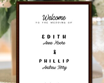May include: A white wedding sign with a brown frame. The sign says "Welcome to the wedding of Edith Anne Moore & Phillip Andrew Terry September 28, 2024 #GETWED".