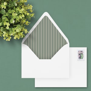 May include: A white envelope with a green and white striped liner. The envelope has a flap on the top and a white paper insert. A postage stamp with a floral design is on the right side of the envelope.