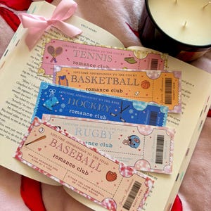 Pode incluir: Cinco marcadores de livros em forma de bilhete rosa e laranja com fundo branco e texto preto. Os marcadores apresentam diferentes desportos: ténis, basquetebol, hóquei, râguebi e basebol. Cada marcador tem o texto "Admissão vitalícia para o campo/campo/pista/campo" e "Clube romântico".