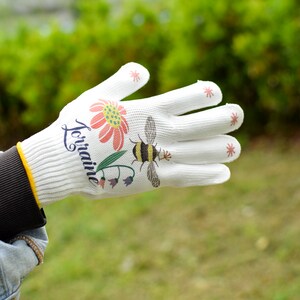 May include: White gardening glove with a floral design and the word "Lorraine" printed on it. The glove has red stars on the fingertips.