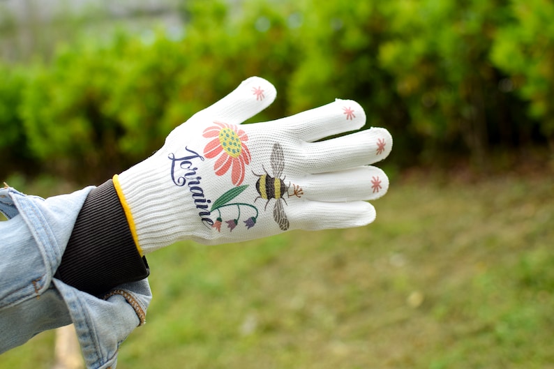 May include: White gardening glove with a floral design and the word "Lorraine" printed on it. The glove has red stars on the fingertips.