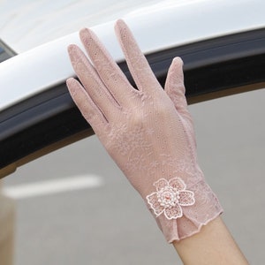 May include: A pair of pink lace gloves with a delicate floral embellishment on the wrist.