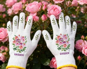 May include: White gardening gloves with a yellow cuff and floral design. The gloves feature a bouquet of pink, purple, and red flowers with the word "GARDEN" printed below. Green leaf accents adorn the fingers.