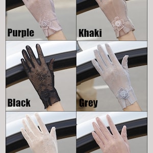May include: Six pairs of sheer lace gloves with a floral embellishment on the wrist. The gloves are in the colors purple, khaki, black, grey, white, and pink.