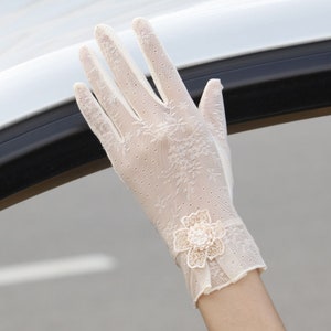 May include: White lace gloves with a delicate floral design and a small pearl-embellished flower accent.