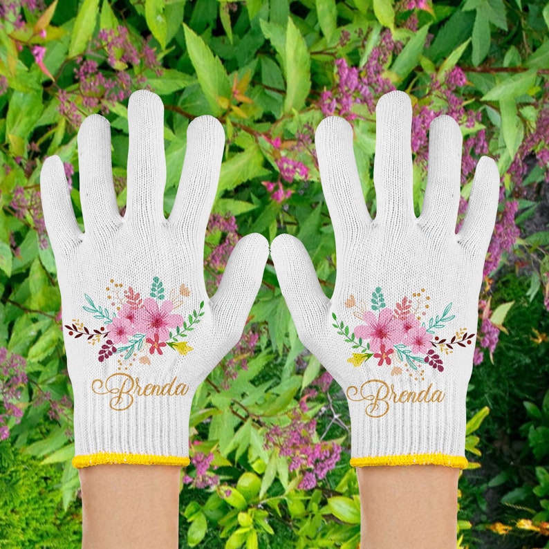 May include: A pair of white gardening gloves with a floral design and the name "Brenda" embroidered on each glove.