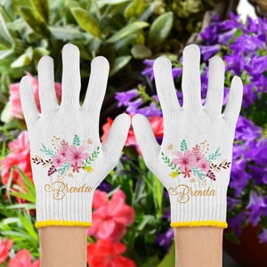 May include: A pair of white gardening gloves with a floral design and the name "Brenda" embroidered on each glove.