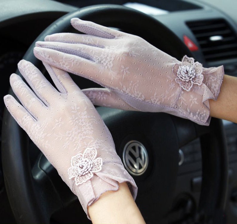 May include: A pair of light purple lace gloves with a floral design. The gloves have a delicate, sheer fabric and are adorned with small, white flowers.