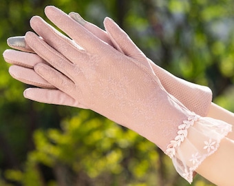 May include: A pair of pink lace gloves with a delicate floral pattern. The gloves have a lace trim at the wrist.