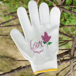 May include: White gardening gloves with a floral design and the letter "M" embroidered on the back of the hand.