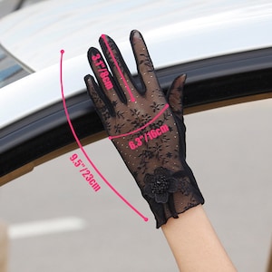 May include: Black lace gloves with a floral design and a black flower embellishment. The gloves measure 9.5 inches long and 3 1/8 inches wide.