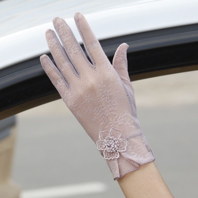 May include: A pair of light purple lace gloves with a small flower embellishment on the wrist.