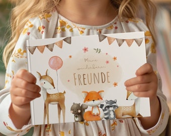 Puede incluir: Una niña sostiene una tarjeta blanca con una ilustración de acuarela de animales del bosque. La tarjeta dice "Meine wunderbaren FREUNDE", que se traduce como "Mis maravillosos AMIGOS".