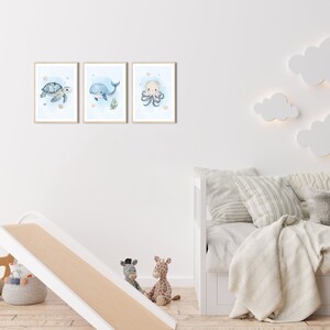 K&ouml;nnte beinhalten: Drei Aquarell-Illustrationen von Meeresbewohnern in einer Kinderzimmer-Umgebung. Die Illustrationen sind gerahmt und an einer wei&szlig;en Wand aufgeh&auml;ngt. Die Illustrationen zeigen eine Schildkr&ouml;te, einen Wal und einen Oktopus.