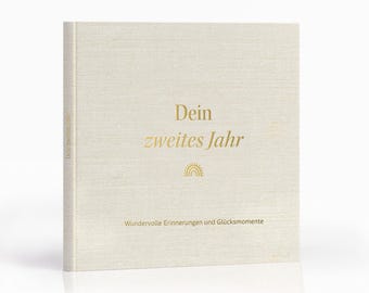 Può includere: Un libro con copertina rigida con una copertina in lino color crema. Il titolo "Dein zweites Jahr" è in lettere dorate, insieme a una grafica arcobaleno. La parte inferiore del libro recita "Wundervolle Erinnerungen und Glücksmomente".