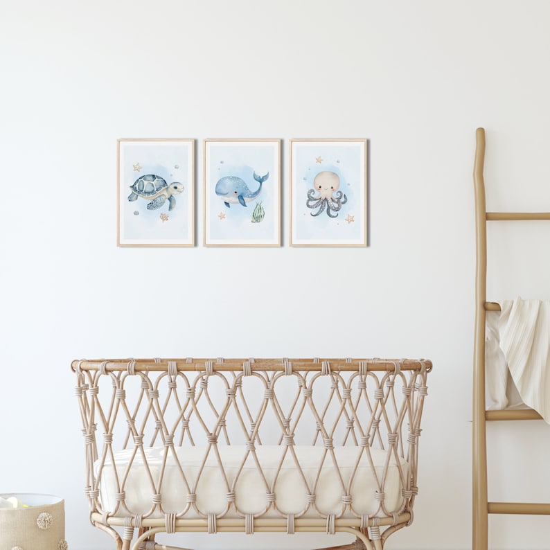 K&ouml;nnte beinhalten: Drei gerahmte Aquarell-Illustrationen von Meeresbewohnern an einer wei&szlig;en Wand. Die Illustrationen zeigen einen blauen Wal, eine Meeresschildkr&ouml;te und einen Oktopus. Die Illustrationen sind vor einem hellblauen Hintergrund mit wei&szlig;en Sternen und Muscheln platziert.
