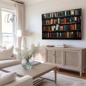May include: A large rectangular wall art print depicting a multi-shelf library filled with numerous colorful books in various shades of blue, red, orange, and brown, displayed in a room with a light wood sideboard and a coffee table.
