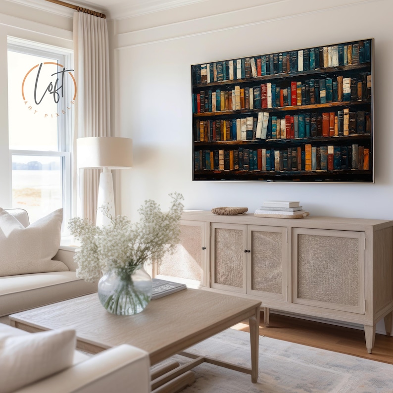 May include: A large rectangular wall art print depicting a multi-shelf library filled with numerous colorful books in various shades of blue, red, orange, and brown, displayed in a room with a light wood sideboard and a coffee table.