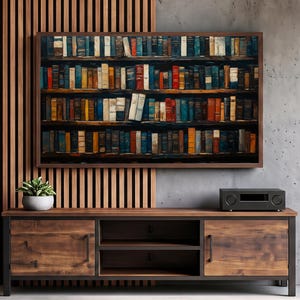 May include: A rectangular wall art print featuring a dense collection of multi-colored books arranged on dark wooden shelves. The artwork is displayed above a wooden media console with two cabinets and open shelving, next to a potted plant.